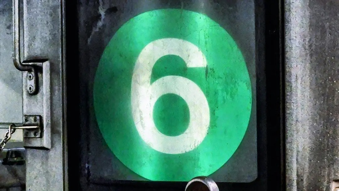 A photographed green circular 6 rollsign on an NYC subway train